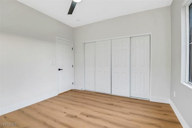 unfurnished bedroom with light wood-style floors, a closet, ceiling fan, and baseboards