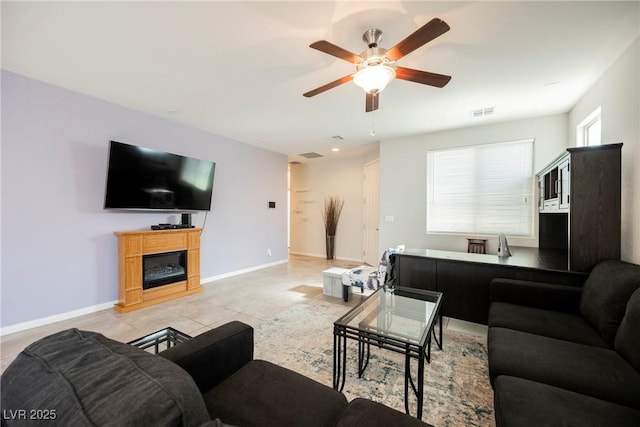 living room with visible vents, baseboards, ceiling fan, and a glass covered fireplace