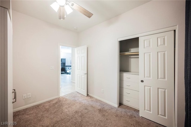 unfurnished bedroom with a closet, light colored carpet, ceiling fan, and baseboards