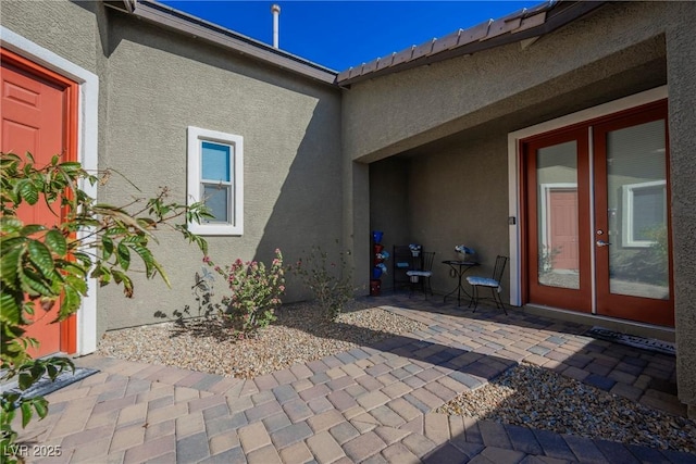 doorway to property featuring a patio, french doors, and stucco siding