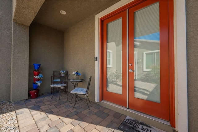 doorway to property with french doors, a patio area, and stucco siding