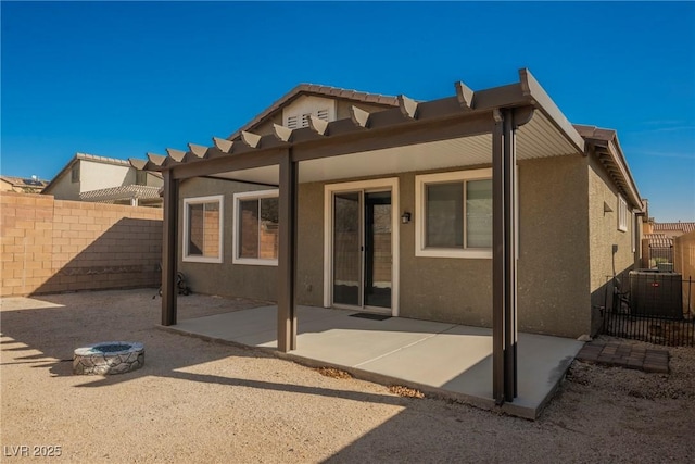 back of house with fence, a fire pit, a patio, and stucco siding