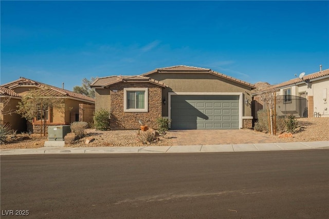 view of front of home with driveway, a garage, stone siding, a tiled roof, and stucco siding