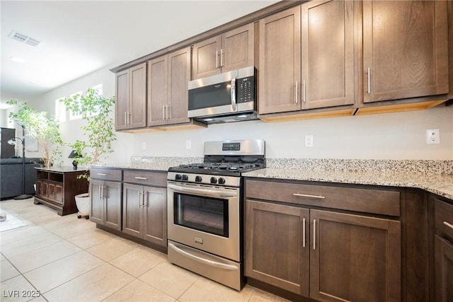 kitchen with light tile patterned floors, visible vents, appliances with stainless steel finishes, light stone counters, and dark brown cabinets