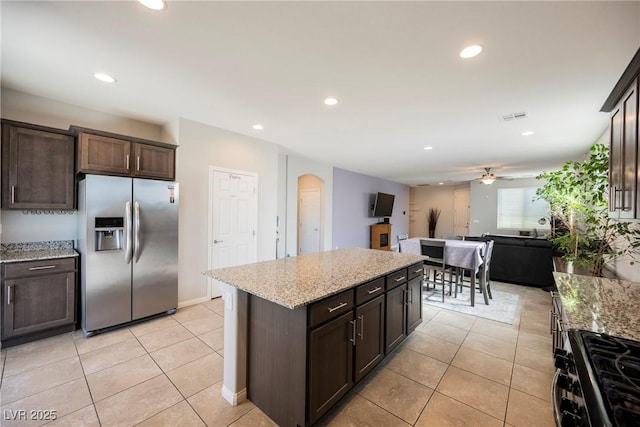 kitchen with stainless steel appliances, visible vents, light stone counters, and dark brown cabinets