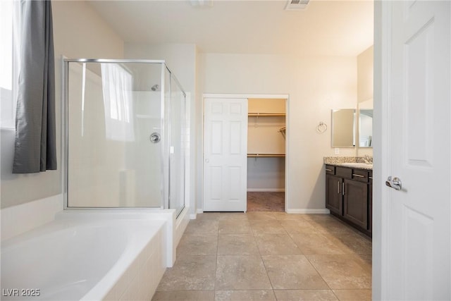 bathroom featuring a stall shower, baseboards, tile patterned floors, a garden tub, and vanity