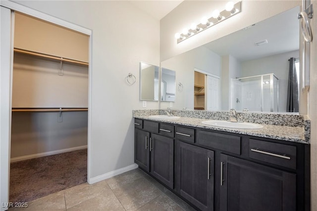 full bath with a spacious closet, a stall shower, and a sink