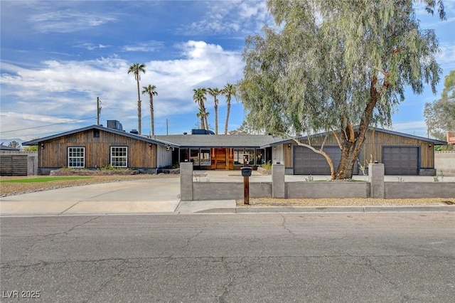 mid-century home with driveway, a garage, and central AC