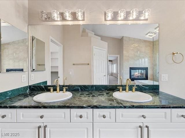 bathroom with a tile fireplace, a sink, and double vanity