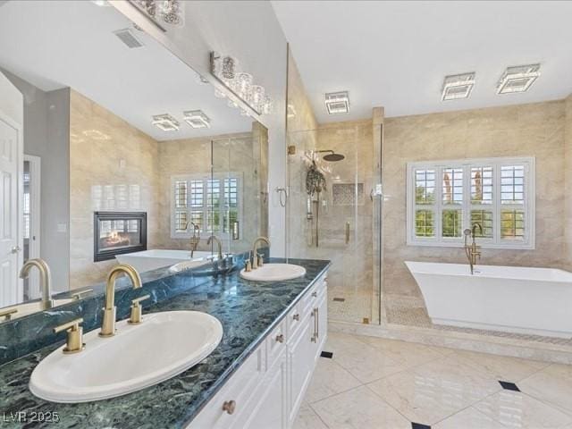 bathroom with a freestanding bath, tile walls, and a sink