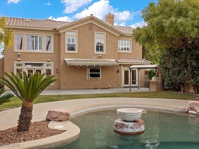 back of property featuring a chimney, a patio area, a tiled roof, and stucco siding