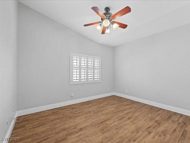 spare room featuring vaulted ceiling, ceiling fan, baseboards, and wood finished floors