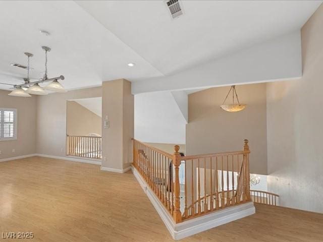 additional living space featuring light wood-style floors, baseboards, visible vents, and vaulted ceiling