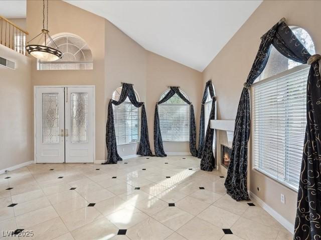 entrance foyer with visible vents, a lit fireplace, light tile patterned flooring, and a wealth of natural light