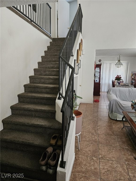 stairway with tile patterned flooring, a towering ceiling, and baseboards