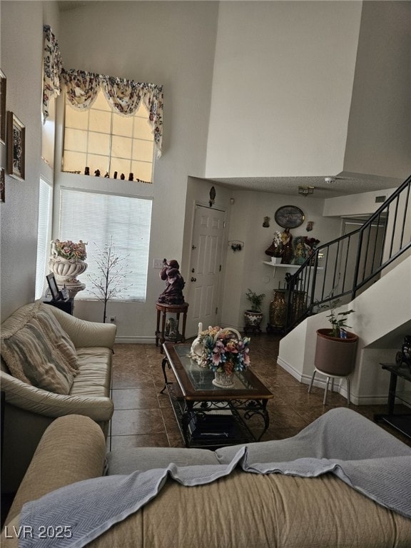 living room with stairway, a towering ceiling, and baseboards