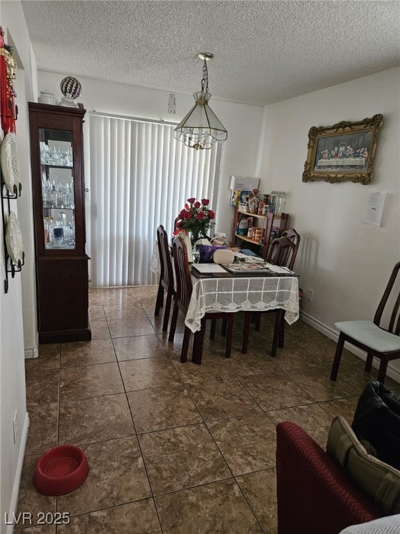 dining area featuring dark tile patterned flooring and a textured ceiling