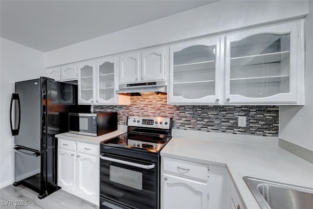 kitchen featuring light countertops, electric range, glass insert cabinets, and under cabinet range hood