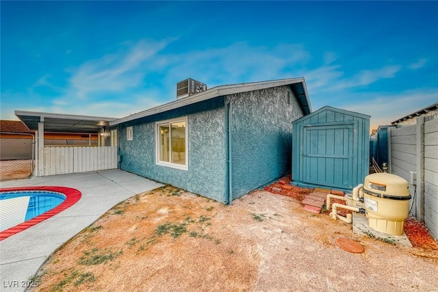 view of side of home with an outbuilding, fence, a storage unit, cooling unit, and stucco siding