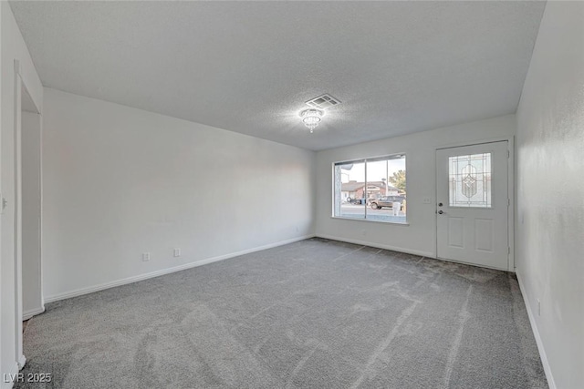 carpeted spare room featuring a textured ceiling, visible vents, and baseboards