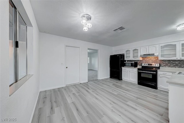 kitchen featuring light countertops, electric range, glass insert cabinets, freestanding refrigerator, and white cabinets