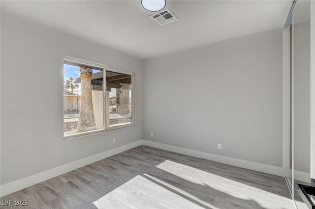 unfurnished room with light wood-type flooring, baseboards, and visible vents