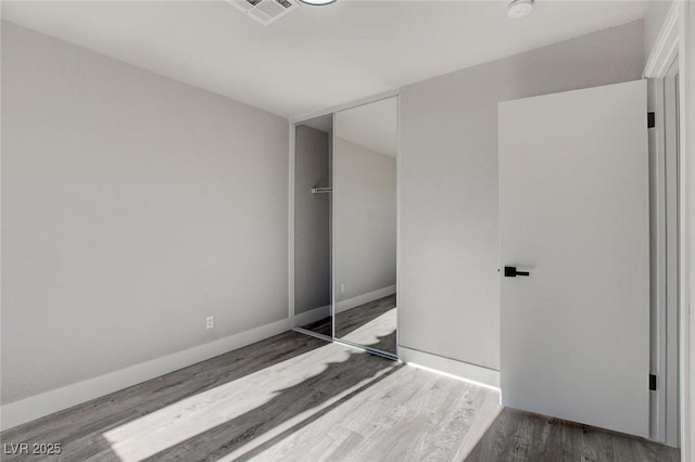 unfurnished bedroom featuring a closet, visible vents, dark wood finished floors, and baseboards