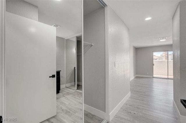 hallway featuring light wood-type flooring, visible vents, and baseboards