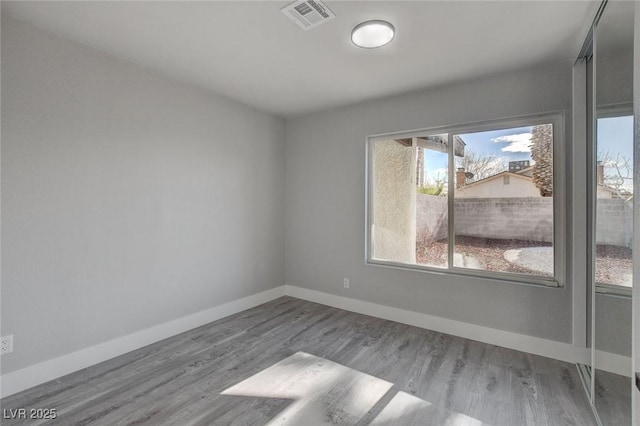 unfurnished room with light wood-type flooring, baseboards, and visible vents