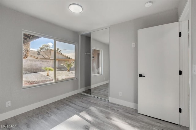 unfurnished bedroom with a closet, baseboards, and light wood finished floors