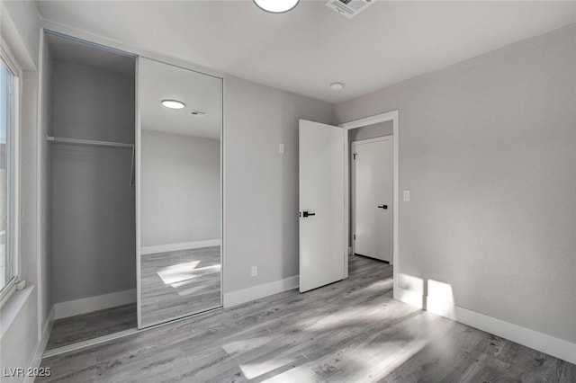 unfurnished bedroom with light wood-style floors, a closet, visible vents, and baseboards