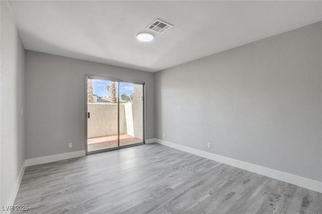 unfurnished room featuring light wood-style flooring, visible vents, and baseboards