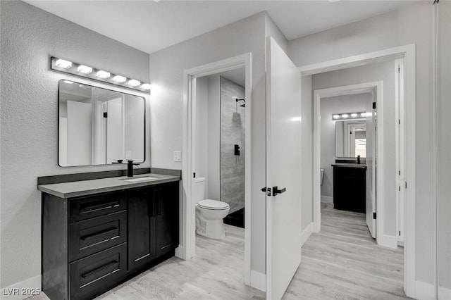 bathroom featuring baseboards, vanity, toilet, and wood finished floors