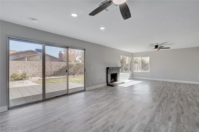 unfurnished living room featuring ceiling fan, recessed lighting, wood finished floors, baseboards, and a brick fireplace