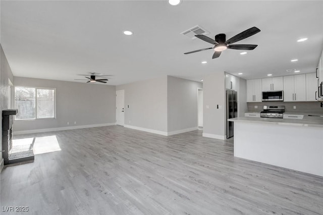 kitchen featuring visible vents, white cabinets, open floor plan, stainless steel appliances, and light countertops