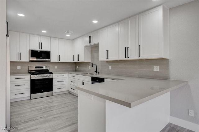 kitchen featuring appliances with stainless steel finishes, light countertops, white cabinets, and a peninsula