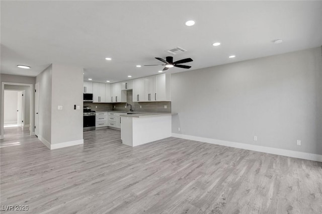 kitchen featuring light countertops, open floor plan, stainless steel range with electric cooktop, white cabinets, and a peninsula