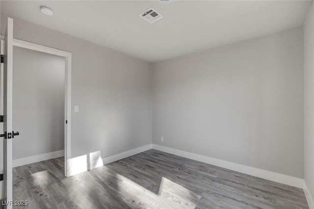 unfurnished room featuring wood finished floors, visible vents, and baseboards