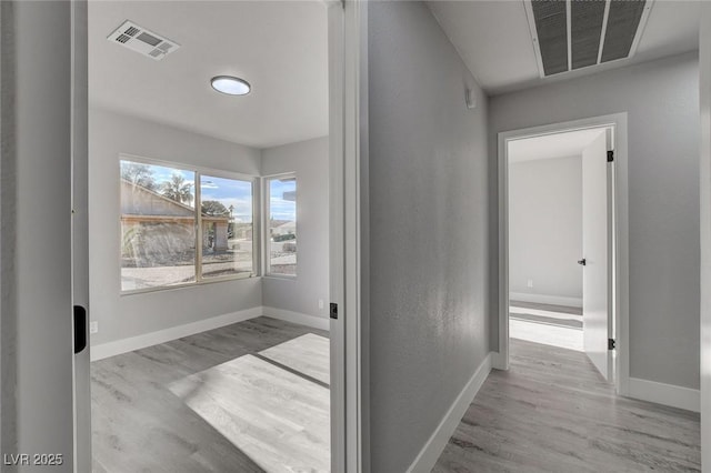 hallway featuring light wood finished floors, visible vents, and baseboards