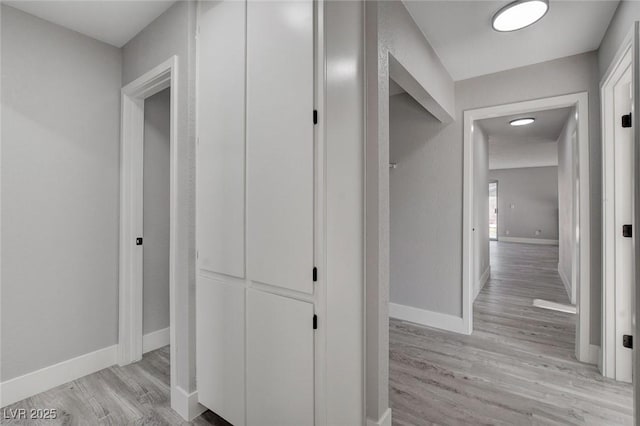 hallway featuring light wood-style floors and baseboards