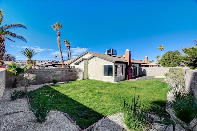 rear view of property with a fenced backyard, a lawn, central AC, and stucco siding