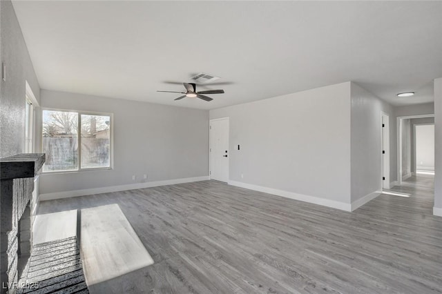 unfurnished living room with baseboards, visible vents, ceiling fan, and wood finished floors