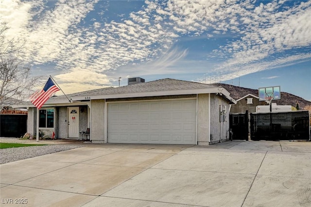 view of front facade with a garage, driveway, fence, and stucco siding