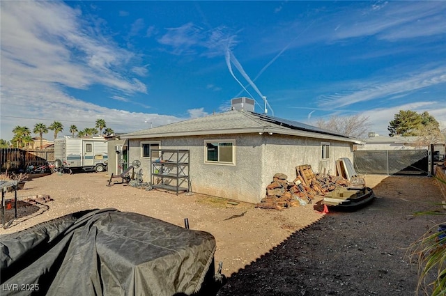 view of home's exterior featuring solar panels, fence, and stucco siding