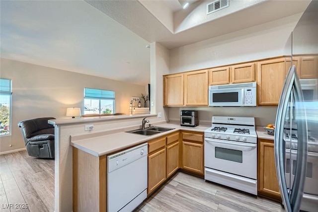 kitchen with white appliances, visible vents, a peninsula, light countertops, and a sink