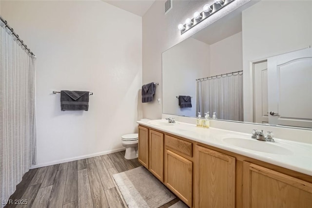 bathroom with double vanity, wood finished floors, a sink, and visible vents