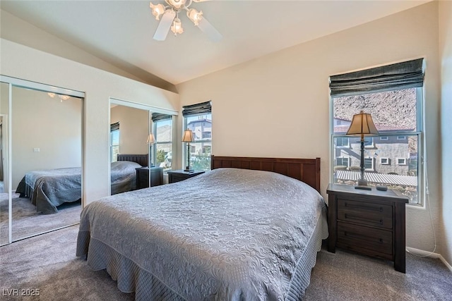 carpeted bedroom featuring ceiling fan, vaulted ceiling, and multiple closets