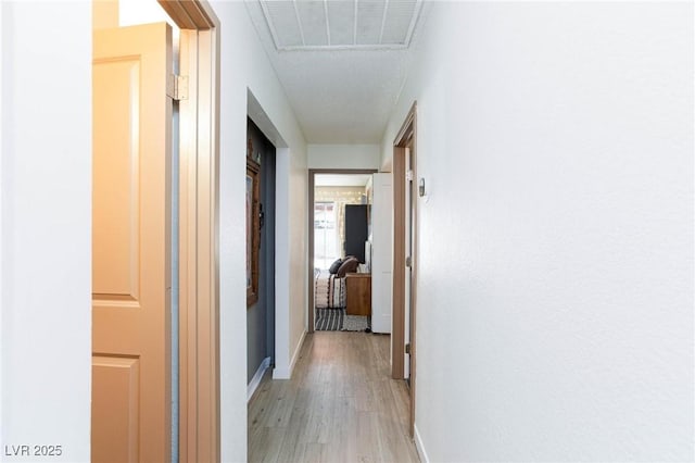 corridor featuring light wood-style flooring, visible vents, and baseboards