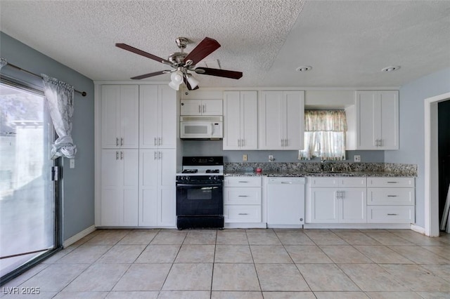 kitchen with light tile patterned floors, stone countertops, white cabinetry, a sink, and white appliances