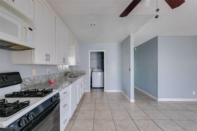 kitchen with black range with gas cooktop, white microwave, washer / dryer, and white cabinetry